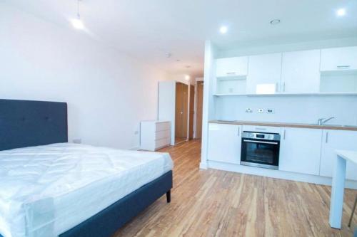 曼彻斯特Luxury Apartment near Media City的一间卧室配有一张床,厨房配有白色橱柜