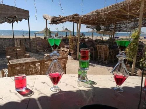 拉斯苏德尔Blue Lagoon Village Ras Sidr (قرية بلولاجون راس سدر) (عائلات فقط)的坐在海滩附近的桌子上,四杯酒