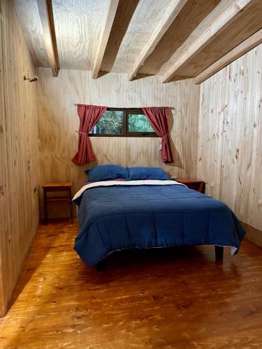 蒙特港Hostería Lenca的一间卧室配有一张带蓝色床单的床和一扇窗户。