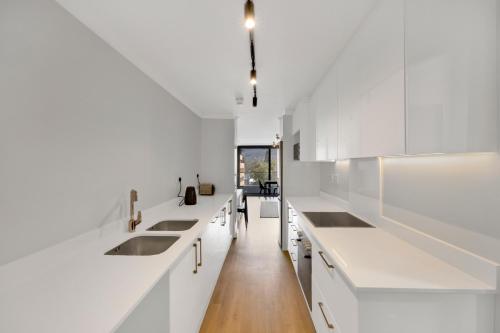开普敦Newlands Peak One-Bedroom Unit的白色的厨房,配有白色的橱柜和长长的走廊