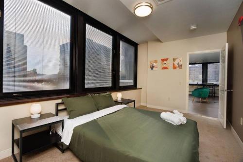 匹兹堡Luxe City Views in DT Pittsburgh VALET GYM WIFI的一间卧室设有一张带大窗户的绿色大床