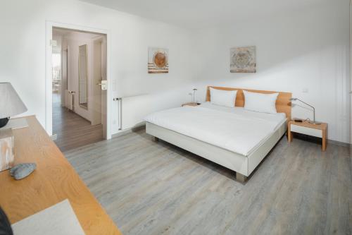 诺德奈Meerliebe的卧室配有白色的床,铺有木地板