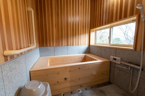 大村市鉢巻山荘的带窗户的浴室内的木浴缸
