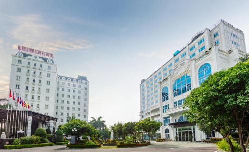 宁平宁平传奇酒店的白色的大建筑,拥有蓝色的窗户和树木