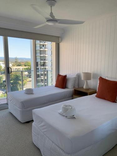 黄金海岸太平洋瑞杰斯海滨假日公寓式酒店的带大窗户的客房内的两张床