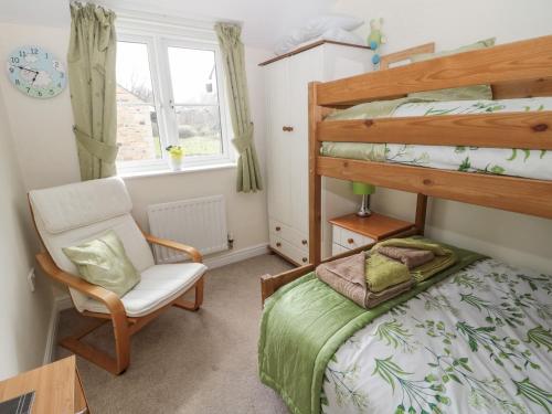 GlantonRamblers Cottage的一间卧室配有双层床和椅子