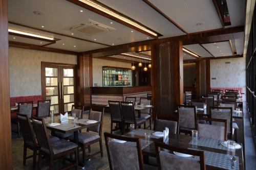 戈尔哈布尔Blisss Hotel Kolhapur的一间在房间内配有桌椅的餐厅