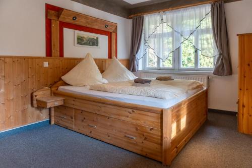 巴特尚道Pension Schrammsteinbaude的卧室设有一张大木床,位于窗户前