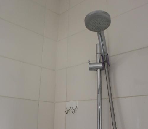 温特和克Abigail's Studio Apartment @ Trift Tower的浴室铺有白色瓷砖,配有淋浴头。