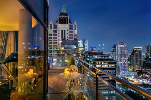 曼谷Bandara Silom Suites, Bangkok的一个带桌椅的阳台,享有城市天际线