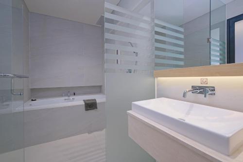 三宝垄Quest Hotel Prime Pemuda - Semarang的白色的浴室设有水槽和浴缸。