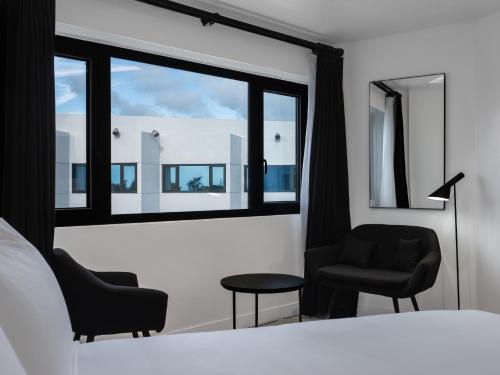 塔穆宁Hotel Tano Guam的一间卧室配有两把椅子、一张床和窗户