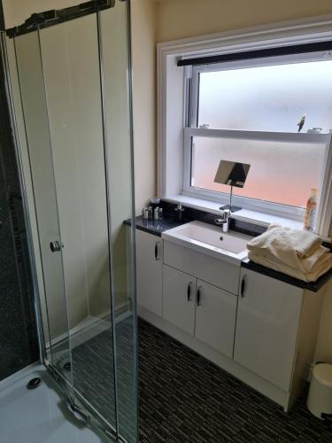 韦茅斯Marden guest house的带淋浴和盥洗盆的浴室以及窗户。