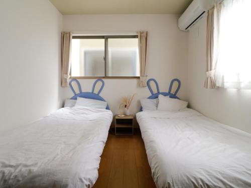富士河口湖貸別荘 ウサギの郷的带窗户的客房内设有两张单人床。