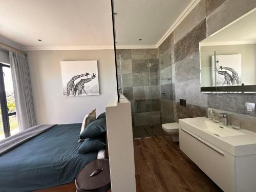 莫塞尔湾Luxury Home located on Pinnacle Point Golf Estate的一间卧室配有一张床,浴室设有水槽