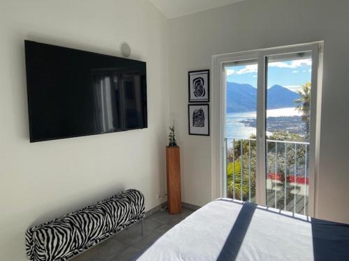 洛迦诺科里纳公寓式酒店的一间卧室设有一张床、一台电视和一个窗口。