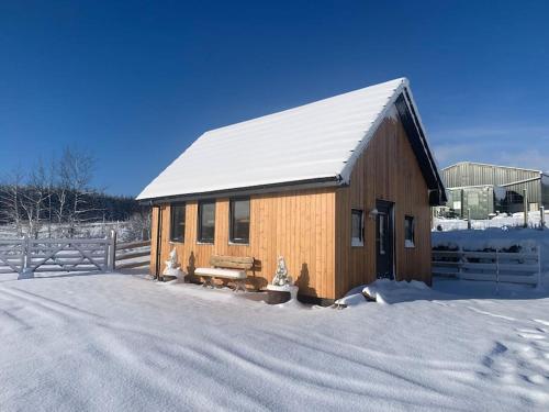 SkeabostCruachan Cabin的一座带雪盖屋顶的木制建筑