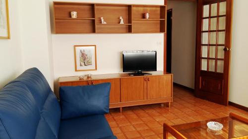 格罗韦Apartamentos Turisticos Arosa Ogrove的客厅配有蓝色的沙发和电视
