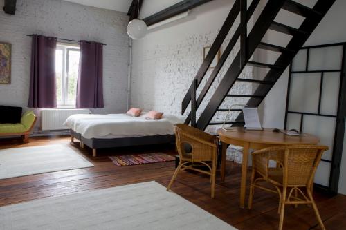 SoigniesLes Greniers de Madelgaire的一间卧室配有一张床、一张桌子和一个楼梯