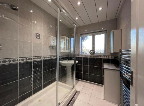 索利赫尔Solihull 5 Bed Home near NEC/Bham airport/JLR/HS2的一间带玻璃淋浴和水槽的浴室
