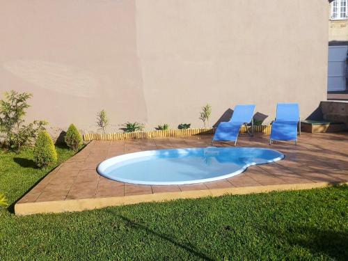 Esteiro4 bedrooms house at Esteiro 53 m away from the beach with enclosed garden and wifi的一个带2把蓝色椅子的游泳池和一个庭院