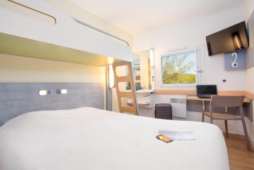 弗雷瑞斯Ibis Budget Fréjus Capitou的一间酒店客房,配有一张白色的床和一张书桌
