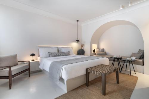 易莫洛林Akra Suites & Spa的白色卧室配有一张大床和椅子