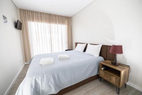 维亚纳堡Meirinha House的卧室配有白色的床和2条毛巾