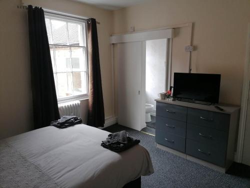 阿什比德拉祖什The Queens Head的一间卧室配有一张床、一台电视和一个梳妆台
