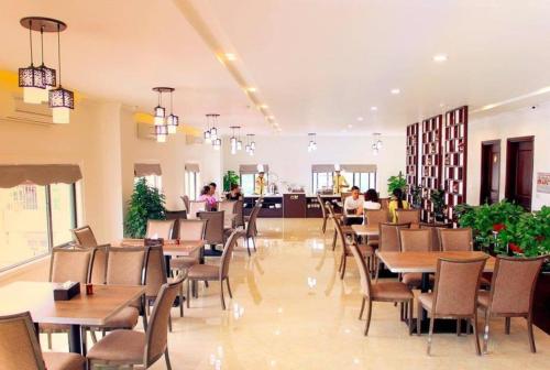 老街市Cao Minh Hotel的餐厅设有桌椅,背景人员