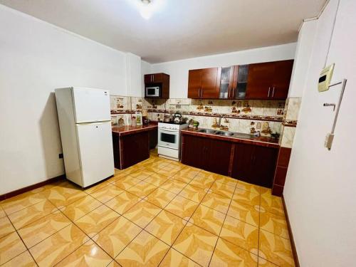 塔克纳Departamento Amplio Pérez Gamboa的厨房配有白色冰箱和木制橱柜。