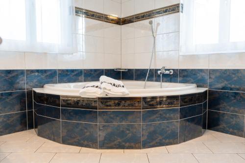 NesslauSchlafen zur Brauerei St. Johann的浴室设有浴缸,铺有蓝色瓷砖。
