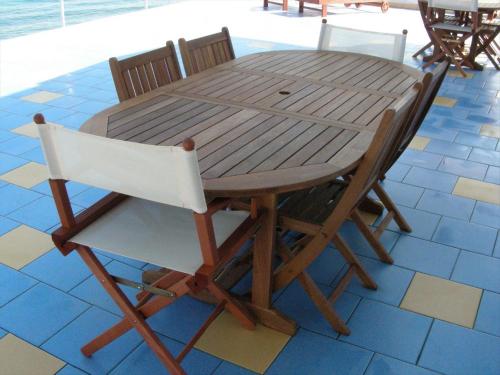 San SabaAppartamenti Sole Mare - Affitto minimo settimanale - Weekly minimum rent的一张木桌和两把椅子围坐在桌子旁