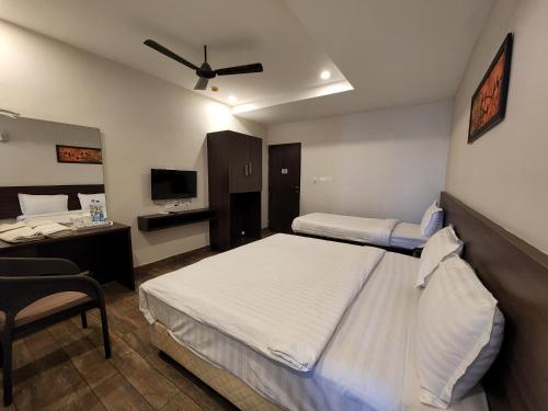 蒂鲁帕蒂HOTEL PARK KRISHNA的酒店客房设有两张床、一张桌子和一台电视。