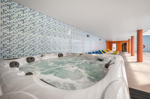 蒙特里尔Hotel Colmeia的浴室设有蓝色瓷砖,配有按摩浴缸。
