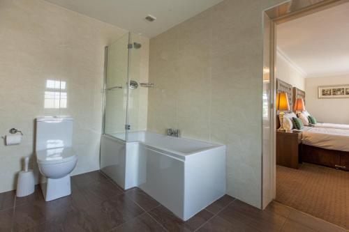 基拉尼城堡旅舍的带浴缸和卫生间的浴室以及1张床。