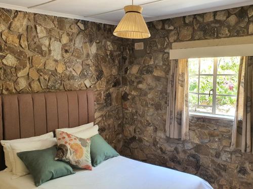 JuliasdaleBeautiful 1-Bed Cottage in Juliasdale的一间卧室设有石墙和一张带枕头的床。