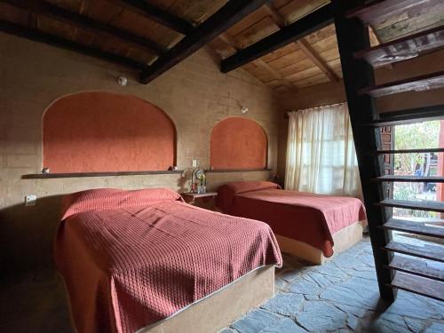 塔斯科·德·阿拉尔孔Hotel SPA Campestre Los Adobes的红色床单的客房内的两张床
