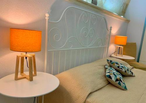 吉诺萨Al Vicoletto的一间卧室配有一张带两张桌子和两盏灯的床。