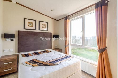 大雅茅斯Luxury Caravan Nearby The Beautiful Scratby Beach In Norfolk Ref 50001a的一间卧室设有一张床和一个大窗户