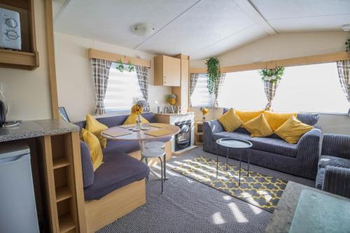 大雅茅斯Cosy Caravan By The Sea At California Cliffs Holiday Park In Norfolk Ref 50006c的厨房以及带沙发和桌子的客厅。