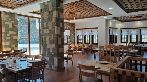 培拉特Pupa Winery Serene Stay的餐厅设有木桌和椅子以及大窗户。