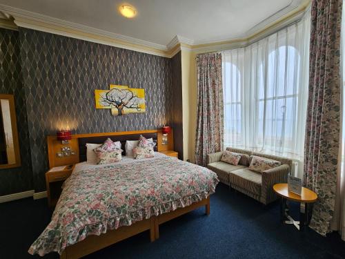 兰迪德诺Iris Hotel Llandudno的一间卧室配有一张床、一张沙发和一个窗口