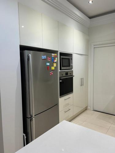 悉尼Luxury sweet room的厨房配有不锈钢冰箱和微波炉。