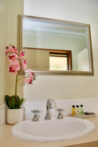 沃伯顿Green Gables Warburton - King Garden Suite的浴室水槽设有镜子和花瓶
