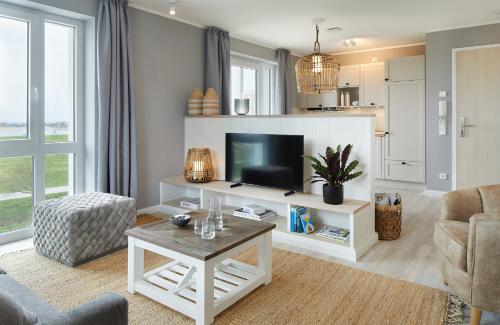 比苏姆Beach Apartments Büsum的客厅配有电视、沙发和桌子
