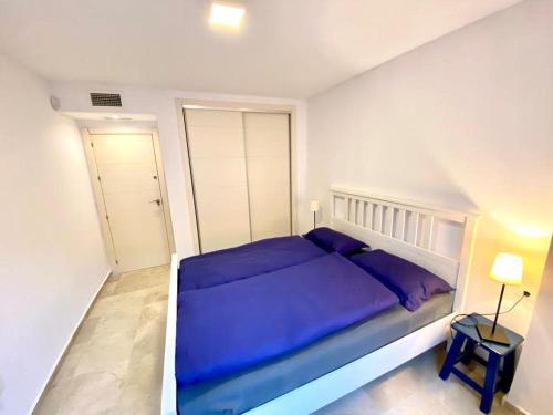 阿尔加德萨Apartment Alcaidesa的一间白色客房内的蓝色床卧室