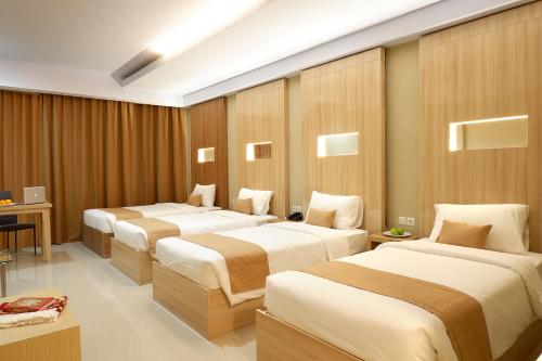 LepoleopSahid Azizah Syariah Hotel and Convention Kendari的酒店客房设有三张床和一张书桌