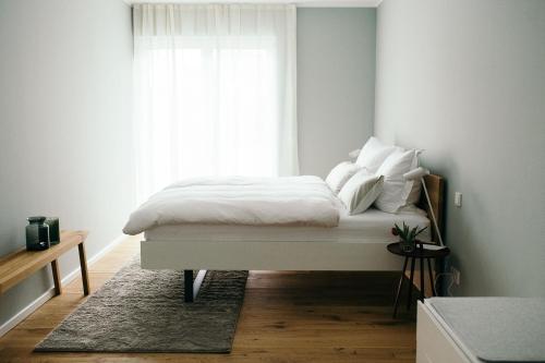 特里滕海姆Moselhaus by Clüsserath-Wittmann的一间卧室配有一张带白色床单的床和一扇窗户。