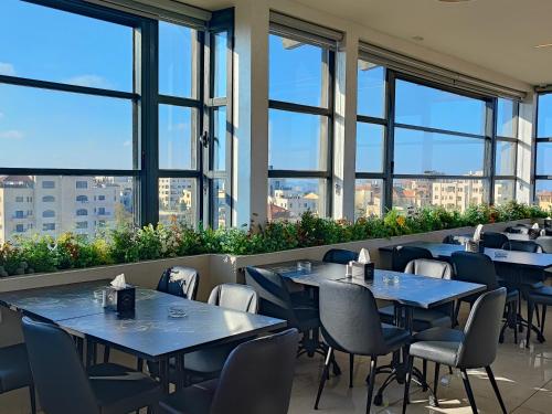 拉马拉Caesar Hotel Ramallah的餐厅设有桌椅和大窗户。